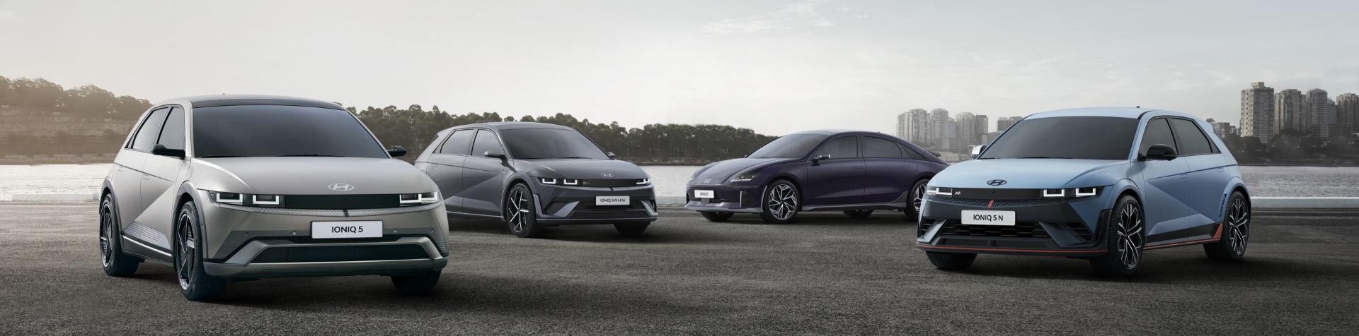 The IONIQ Lineup parked in front of a river with a city skyline in the background.