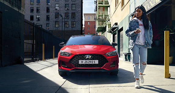 A woman and front view of red veloster parking on the road 