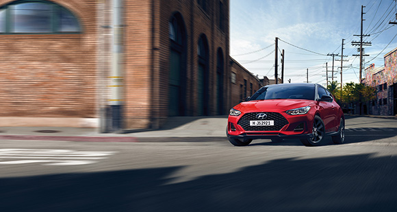 Left side rear view of red veloster driving on the road